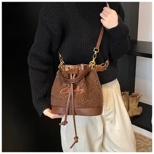 Brown plush bucket bag with leather accents and embroidery shown in use by a model