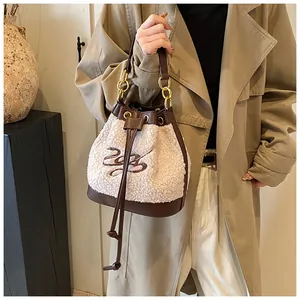 Close-up of fluffy white fleece bucket bag featuring brown leather trim and gold chain handle