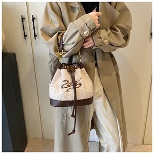 Detail of plush cream bucket bag with brown leather trim and elegant gold hardware accents