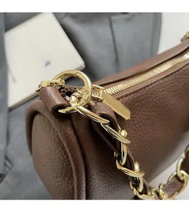 Gros plan du sac en cuir marron foncé avec texture litchi et chaîne dorée brillante