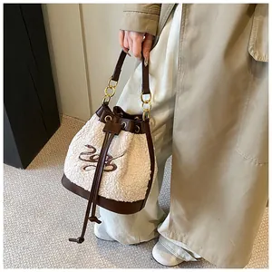 Detail of plush bucket bag featuring white fleece, brown leather trim and metal chain