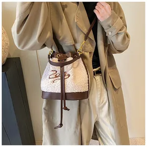 Detail of plush bucket bag with white faux fur and brown leather trim on beige coat