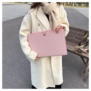 Détail de la housse d'ordinateur en toile rose montrant la texture tissée et le bouton