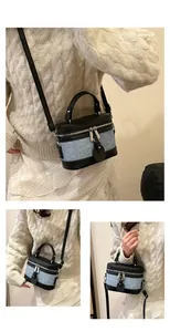 Detail of blue denim and black leather bucket bag with silver zipper and handle