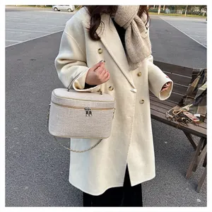 Dettaglio borsa a scatola in tela beige con tessuto strutturato e catena argentata