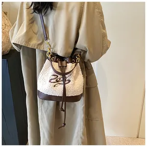 Detail of plush bucket bag with white shearling fabric, brown leather trim, and embroidery