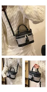 Detail of grey textured fabric and black leather bucket bag with silver hardware accents
