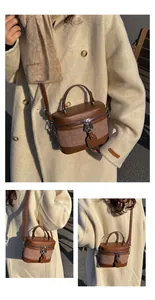 Detail of brown contrast leather bucket bag with top handle and adjustable strap