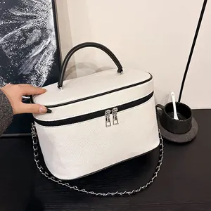 Dettaglio della borsa cosmetica intrecciata bianca con manico nero e cerniera d'argento