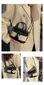 Detail view of contrast color vanity bucket bag with leather trim and shoulder strap