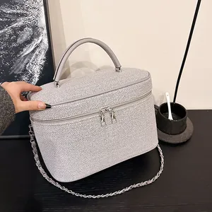 Dettaglio della borsa in tweed grigio con manici in pelle e tracolla a catena d'argento
