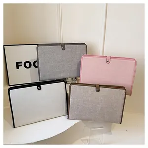 Housses d'ordinateur en toile empilées en gris, rose et beige avec fermoir en cuir