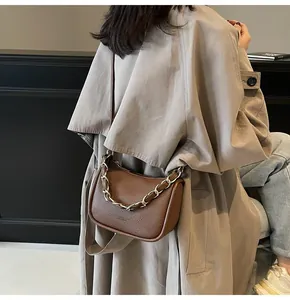 Détail du sac selle en cuir grainé marron avec chaîne dorée et bandoulière réglable
