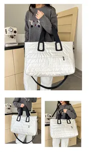 Dettaglio di una grande borsa trapuntata argento lucido con robuste cinghie nere