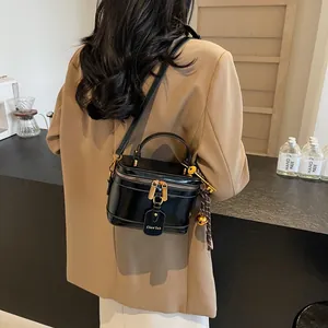 Detail of a vintage-style black leather mini box bag with gold hardware and charms
