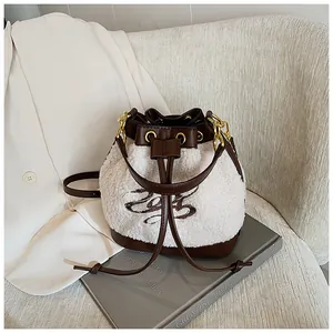 Detail of plush bucket bag featuring white faux shearling and brown leather drawstring