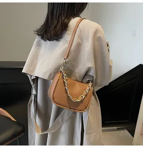 Gros plan du sac demi-lune en cuir caramel avec chaîne dorée et texture grainée