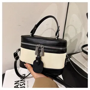 Close-up of contrast leather bucket bag with canvas stitching and metal zippers