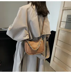 Gros plan d'un sac en cuir marron avec chaîne dorée sur un trench-coat beige chic