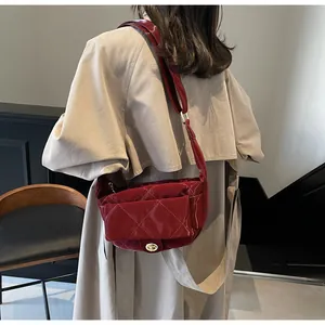 Detail of red quilted patent leather shoulder bag with golden lock on beige coat