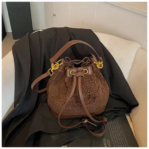 Detail of plush bucket bag with leather accents on a black blazer and white chair