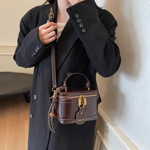 Detail of vintage dark brown leather vanity box bag with gold zipper and shoulder strap