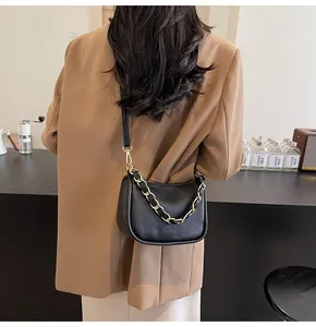 Détail du sac bandoulière en cuir noir grainé avec accents de chaîne dorée chic