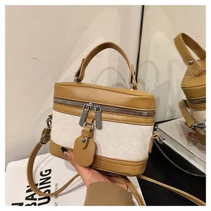 Detail of minimalist bucket bag with beige canvas and tan leather trim and silver hardware