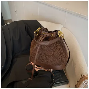 Detail of plush brown bucket bag showing fuzzy texture, leather drawstring, and embroidery
