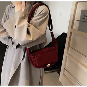 Close-up of wine red quilted shoulder bag featuring a gold clasp and shiny leather texture