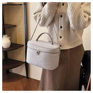 Borsa da trucco in tela grigia con tracolla a catena e manico in ambiente domestico