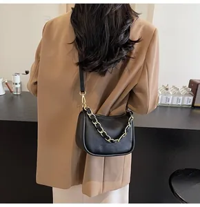 Détail du sac bandoulière en cuir grainé noir avec une chaîne dorée audacieuse