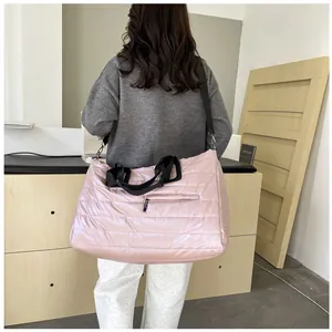 Grande borsa trapuntata rosa pallido con tracolla nera mostrata su una modella