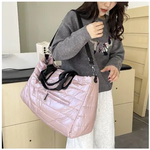 Grande borsa trapuntata rosa indossata da modella con manici neri e tracolla regolabile