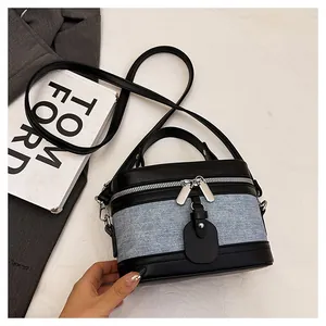 Close-up of contrast denim and black leather bucket bag with silver zipper detail