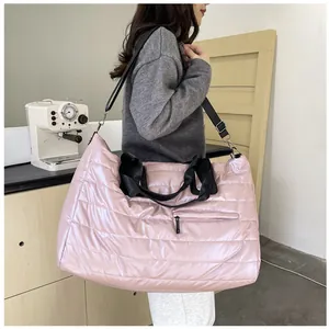 Dettaglio della borsa da viaggio rosa trapuntata con tracolle nere e tasca con zip