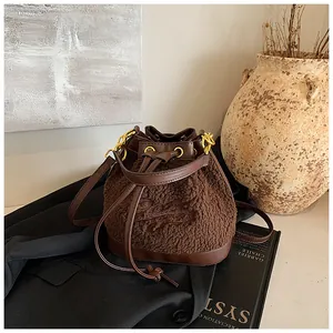 Detail of plush fleece bucket bag with dark brown leather drawstring and embroidery