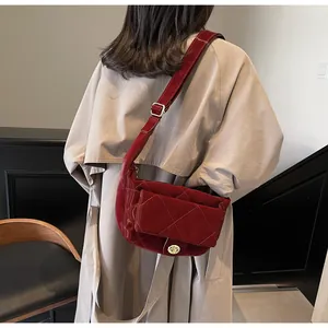 Detail of red quilted patent leather saddle bag with gold metal twist lock and strap
