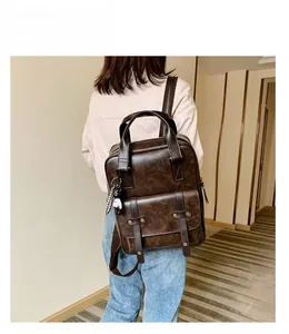 Detail of vintage dark brown faux leather backpack with retro straps and cat charm