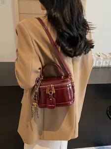 Retro burgundy patent leather box shoulder bag with gold hardware shown on a model