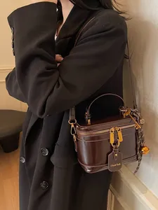 Retro dark brown box bag in glossy leather with gold hardware worn as a crossbody