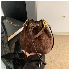 Detail of plush bucket bag with leather drawstring, gold hardware and embroidered accents