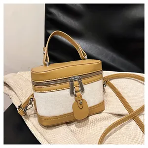 Detail showing the cream canvas and ginger leather stitching on structured bucket bag
