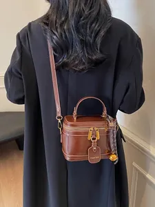 Retro brown box-shaped crossbody bag with dual zippers and handle shown on model back