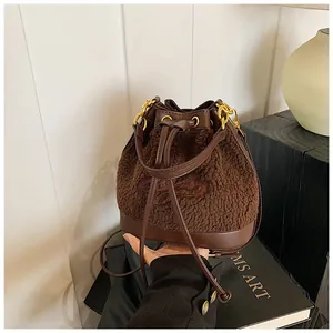 Close-up of brown plush bucket bag with leather trim and gold metal buckle hardware