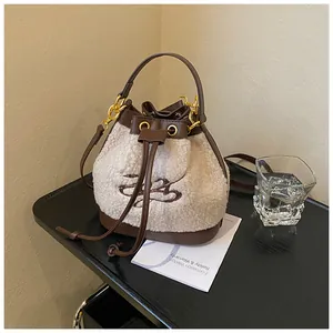 Detail of plush fleece bucket bag showing contrast brown leather drawstring and embroidery