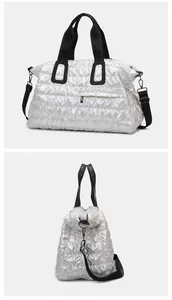 Close-up of white quilted travel bag showing side zipper pocket and black strap detail