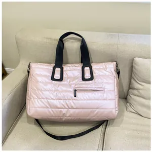 Borsa tote rosa trapuntata con manici neri su divano beige, dettaglio tasca frontale