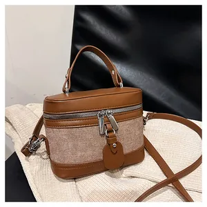 Detail of retro bucket bag featuring brown leather and canvas patchwork with silver hardware