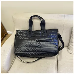 Dettaglio borsa da viaggio trapuntata nera con finitura lucida e manici rinforzati